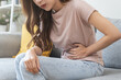 © KMPZZZ - Flatulence asian young woman intolerance hand in stomach ache, suffer from food poisoning, abdominal pain and colon problem, gastritis or diarrhoea when at home. Patient belly, abdomen or inflammation