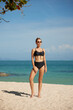 © South House Studio - Beautiful young woman in black swimsuit and sunglasses on the beach