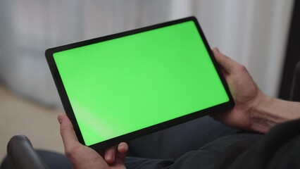 Sticker - Man sitting indoors on a chair with tablet pc with green screen