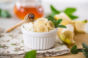 Wall Mural - crumbly organic cottage cheese with honey and bananas in a ceramic bowl