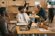 Multiracial, inter-generational businesspeople working at modern co working space. Brunette girl interrupting her black male colleague while he is talking