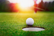 Golf balls and golf club on green grass shiny light sunse