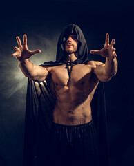 Wall Mural - Scary muscular young man with pointed hood and cape