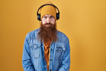 Canvas Print - Caucasian man with long beard listening to music using headphones depressed and worry for distress, crying angry and afraid. sad expression.