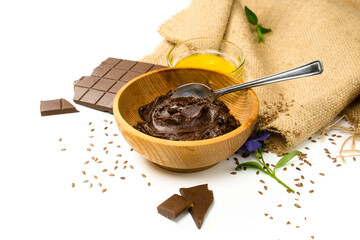 Chocolate paste in wooden bowl and ingredients. Chocolate butter and honey on white background. Homemade carob butter with ingredients. Healthy sweet food concept