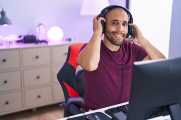 Poster - Young latin man streamer smiling confident sitting on table at gaming room