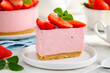 A slice of no bake strawberry cheesecake on a white plate. Close up. Selective focus