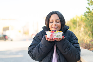 Wall Mural - Young woman  holding a bowl of fruit at outdoors