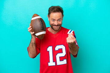 Wall Mural - Middle age caucasian man playing rugby isolated on blue background making money gesture