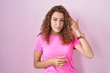 Sticker - Young caucasian woman standing over pink background shooting and killing oneself pointing hand and fingers to head like gun, suicide gesture.