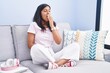 © Krakenimages.com - Young hispanic woman sitting on the sofa at home bored yawning tired covering mouth with hand. restless and sleepiness.
