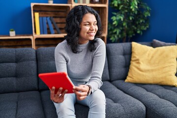 Sticker - Young latin woman using touchpad sitting on sofa at home