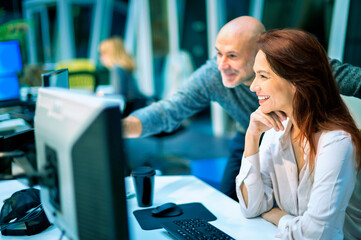 Group of business people sitting and standing together at the office surrounded computers and working together