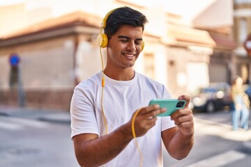 Sticker - Young hispanic man smiling confident playing video game at street