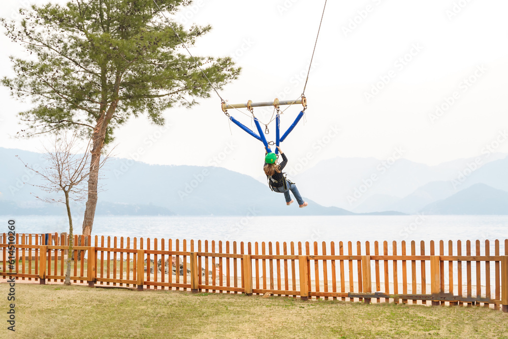 Teenage teen girl bungee flying in rope amusement park. Climbing ...