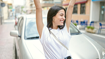 Wall Mural - Young beautiful hispanic woman smiling confident standing with winner expression at street