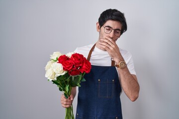 Canvas Print - Young hispanic man holding bouquet of white and red roses bored yawning tired covering mouth with hand. restless and sleepiness.