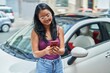 © Krakenimages.com - Young chinese woman using smartphone leaning on car at street