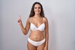 © Krakenimages.com - Young hispanic woman wearing white lingerie showing and pointing up with finger number one while smiling confident and happy.