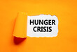 © Dzmitry - Hunger crisis symbol. Concept words Hunger crisis on beautiful white paper on a beautiful orange background. Business, support and Hunger crisis concept. Copy space.