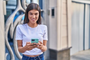 Canvas Print - Young beautiful hispanic woman smiling confident using smartphone at street