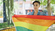 © Krakenimages.com - Young beautiful hispanic woman standing with serious expression holding rainbow flag at park