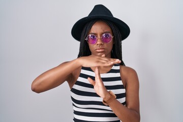 Poster - Young african american with braids wearing hat and sunglasses doing time out gesture with hands, frustrated and serious face