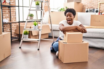 Canvas Print - African american woman sitting on the floor at new home celebrating crazy and amazed for success with open eyes screaming excited.