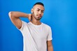 © Krakenimages.com - Young hispanic man standing over blue background suffering of neck ache injury, touching neck with hand, muscular pain