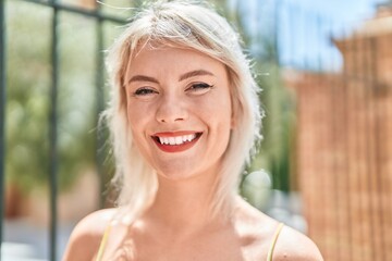 Wall Mural - Young blonde woman smiling confident standing at street