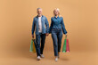 © Prostock-studio - Positive senior man and woman with shopping bags walking