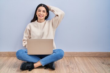 Sticker - Young woman using laptop sitting on the floor at home smiling confident touching hair with hand up gesture, posing attractive and fashionable