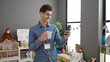 © Krakenimages.com - Young hispanic man preschool teacher using smartphone drinking coffee at kindergarten