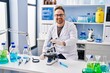 © Krakenimages.com - Middle age caucasian man working at scientist laboratory looking positive and happy standing and smiling with a confident smile showing teeth
