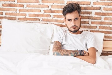 Wall Mural - Young hispanic man sitting on bed with unhappy expression and arms crossed gesture at bedroom