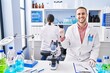 © Krakenimages.com - Young man working at scientist laboratory smiling happy pointing with hand and finger to the side