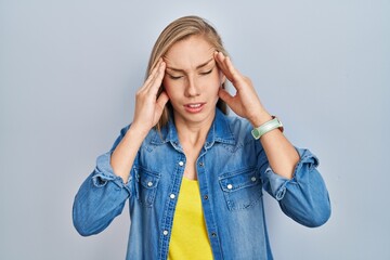 Sticker - Young blonde woman standing over blue background with hand on head, headache because stress. suffering migraine.