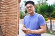 © Krakenimages.com - Young chinese man smiling confident using smartphone at street