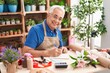 Middle age grey-haired man florist smiling confident writing on notebook at florist