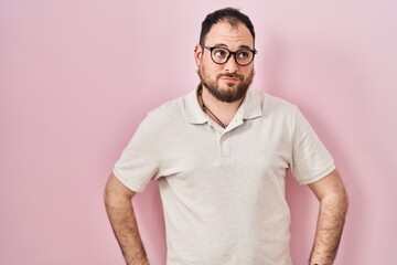 Wall Mural - Plus size hispanic man with beard standing over pink background smiling looking to the side and staring away thinking.