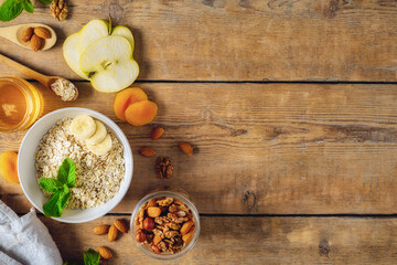 Wall Mural - Dry raw oatmeal with ingredients for cooking healthy breakfast on wooden table with copy space top view