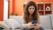 © Krakenimages.com - Young beautiful hispanic woman using smartphone upset at home