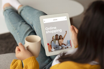 Lady using tablet with online store on screen, drinking coffee at home, enjoy website or mobile app, ad and offer