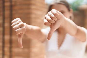 Sticker - Young caucasian woman doing negative sign with thumbs down at street