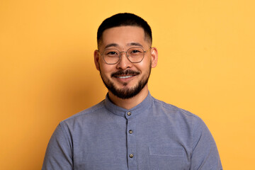 Portrait Of Handsome Young Asian Man In Eyeglasses Posing Over Yellow Background