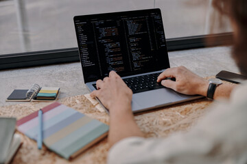 close up of male programer hands write code on laptop sitting in cafe near window