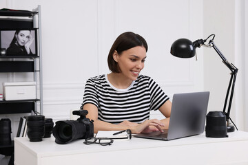 Canvas Print - Young professional photographer with camera working on laptop in modern photo studio