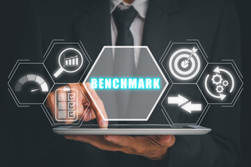 Benchmarking concept, Businessman hand touching on tablet computer with benchmarking icon on virtual screen.