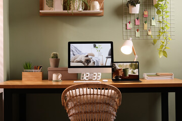 Wall Mural - Stylish workplace with computer, laptop and lamp near olive wall at home