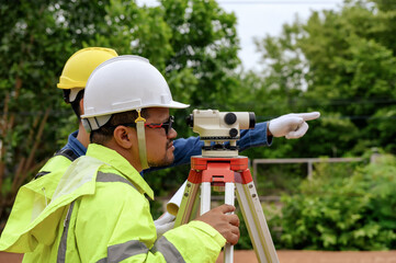 Wall Mural - Close-up Asian surveyor engineer using Surveyor's Telescope equipment to measure ground leveling for cut and fill, started leveling the ground at the construction site.